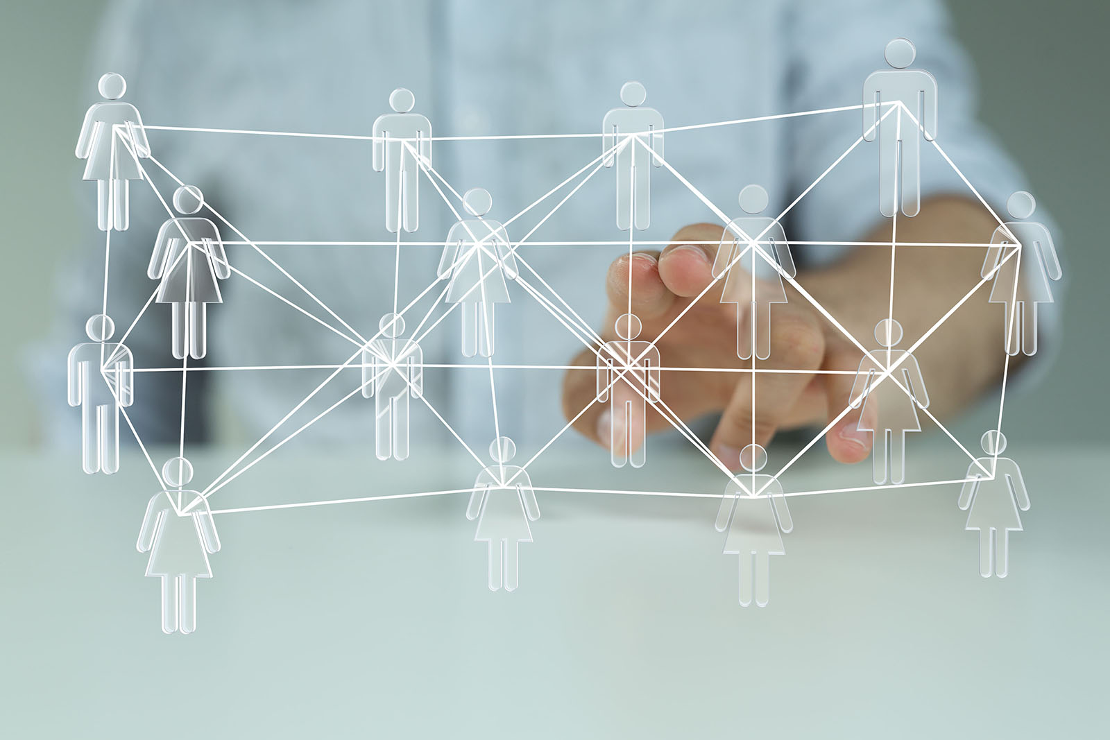 Die linke Hand eines Mannes im weißen Hemd zeigt in den Vordergrund, wo sich weiße Icons von Personen, die wie ein Netz durch weiße Striche miteinander verbunden sind, befinden.